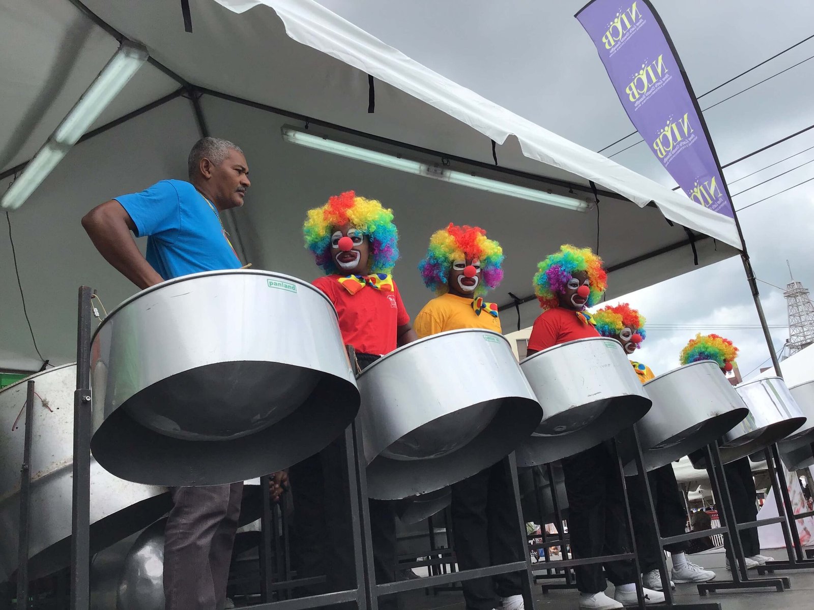 pan for blue primary school steel band performing on stage with clown costume